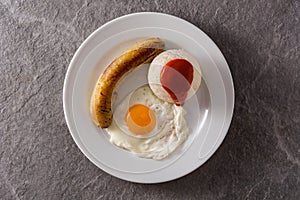 Arroz a la cubana.Typical Cuban rice with fried banana and fried egg on a plate on gray background.