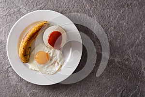 Arroz a la cubana.Typical Cuban rice with fried banana and fried egg on a plate on gray background.