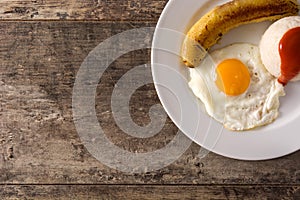 Arroz a la cubana Typical Cuban rice with fried banana and fried egg on a plate on wood