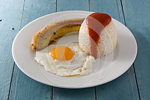 Arroz a la cubana Typical Cuban rice with fried banana and fried egg on a plate on wood