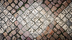 Art background of a pavement paved with small granite square cobblestones in the shape of rhombuses. view from above