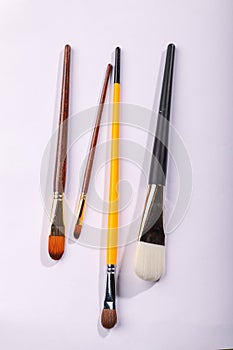 Art brushes of different sizes on a white background. Four painting brushes, vertical shot