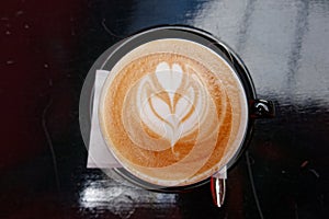 Art cappuccino coffee with heart shaped tree in black cup top view