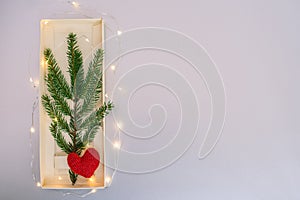 Art Christmas Greeting Card. Christmas tree white glass toys two hearts and natural fir branch of spruce on red paper