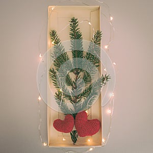 Art Christmas Greeting Card. Christmas tree white glass toys two hearts and natural fir branch of spruce on toned paper