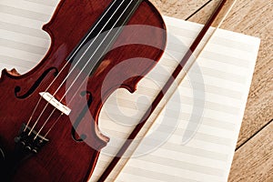 Art of Composing. Close up view of brown violin with a bow lying on sheets for music notes