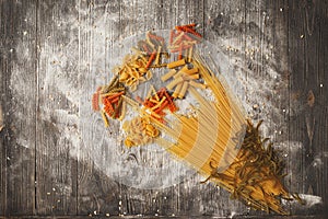 Art composition of bouquet flowers made different types pasta on a black wooden background