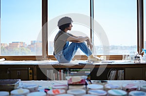 Art, creative and woman painter thinking of idea for painting by a table and window in a studio. Girl designer or artist