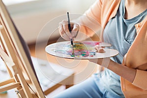 Artist with palette and brush painting at studio