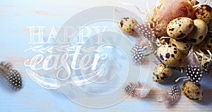 Art Easter banner with eggs and bird feather on light blue background. Top view, flat lay with copy space