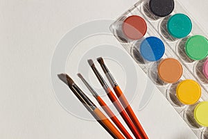 Art equipment: paint and brushes on white paper background