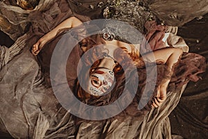 Art Fashion. From above Beautiful young woman in elegant historical dress and with barocco updo hairstyle lying on floor photo