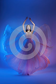 Art fashion beautiful elegant woman in blowing flying dress. Freedom concept in neon color light. Fashion style of flowing dress