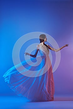 Art fashion beautiful elegant woman in blowing flying dress. Freedom concept in neon color light. Fashion style of flowing dress