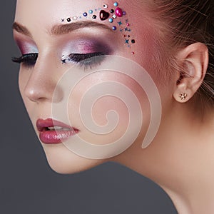 Art makeup over the eyebrows of women many rhinestones of different shapes, beautiful face smooth skin care. Beauty makeup