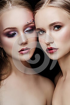 Art makeup two girls hugging, lots of rhinestones of different shapes, beautiful face smooth skin care. Beauty makeup on the face