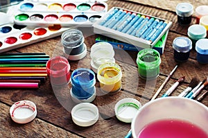 Art of Painting. Paint buckets on wood background. Different paint colors painting on wooden background. Painting set: brushes, pa