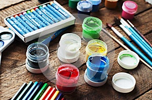 Art of Painting. Paint buckets on wood background. Different paint colors painting on wooden background. Painting set: brushes, pa photo