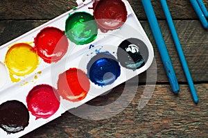 Art of Painting. Paint buckets on wood background. Different paint colors painting on wooden background. Painting set: brushes, pa photo