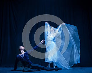 Art performance. Two graceful ballet dancers, man and woman dancing isolated over dark background.