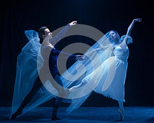 Art performance. Two graceful ballet dancers, man and woman dancing isolated over dark background.