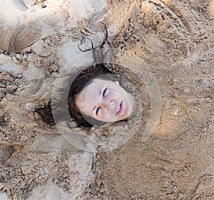 Art photo of beautiful lady buried in the sand