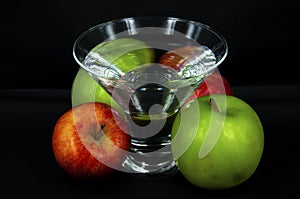 Art photo glass of water red and green apples on a black background