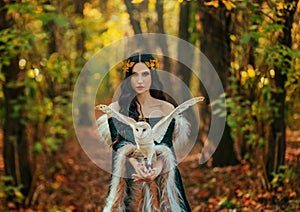 Art photo portrait Fantasy woman goddess elf, white bird barn owl sits on hands flapping wings. Autumn forest trees