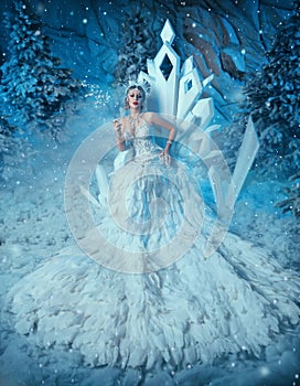 Art photo real people Fantasy woman snow queen sits on ice throne, white long dress train bird feathers crown icicles