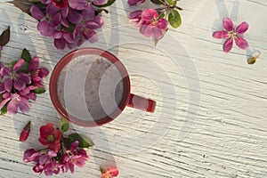 Art pink spring flowers frame with cup on old white wood background.