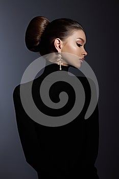 Art portrait woman in black turtleneck. Hair high beam, perfect profile face. Elegant beauty style. Earrings in the ears