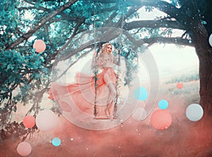 Art princess elf stands swinging on magical forest swing mystical tree. Woman nymph in long pink dress skirt fluttering