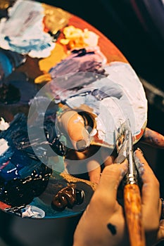 art school acrylic paint on palette brush in hands