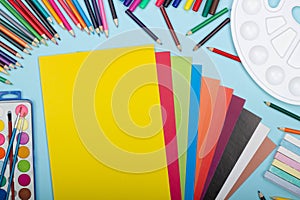 Art school supplies for painting and a set of colored paper on a blue background