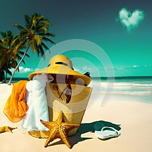 Art Straw hat, bag, sun glasses and flip flops on a tropical beach