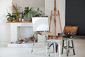 Art studio interior with painting supplies, canvas on easel, paintbrushes, vintage oil paint box