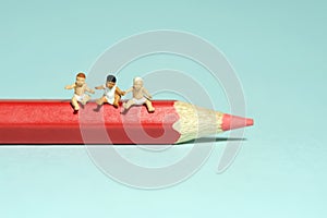 Art study and learning concept. Group of boy toddlers sitting above red pencil color. Isolated on blue background