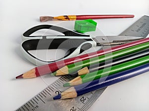 Art supplies Sissors pencil crayons ruler paint brush scattered on a white background photo