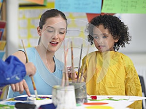 Art Teacher Assisting Cute Girl In Painting