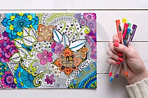 Art therapy, mental health, creativity and mindfulness concept. Flat lay close up on woman hands coloring an adult coloring book.