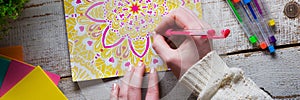 Art therapy, mental health, creativity and mindfulness concept. Flat lay close up on woman hands coloring an adult coloring book.