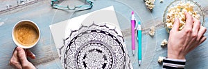 Art therapy, mental health, creativity and mindfulness concept. Flat lay close up on woman hands coloring an adult coloring book.