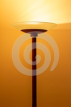 Art view of a modern pole lamp casting light upon a wall corner