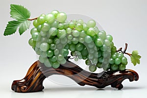 The art work of a bunch of grapes with leaves made of green jade which is placed on the shining wooden base.