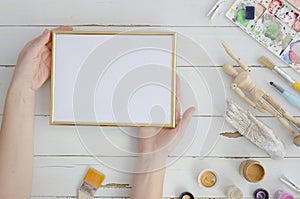 Art work mock up. Gold photo frame with woman artist hands. Space for text, drawing, lettering. Flat lay, top view. Cosy
