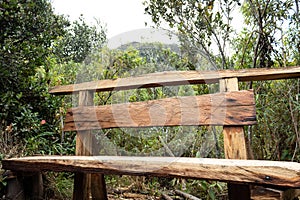 Artesanal Wooden bench bank in middle of trekking path at forest mountains photo