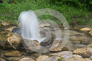 Artesian well. Eruption of spring, natural environment. Stones and water. Clean drinking groundwater erupting out of the ground.