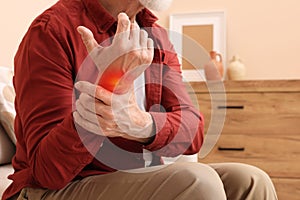 Arthritis symptoms. Senior man suffering from pain in his wrist at home, closeup