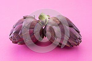 Artichoke flowers, purple edible buds isolated on pink background