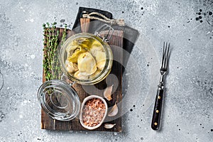 Artichoke hearts marinated in olive oil. Gray background. Top view